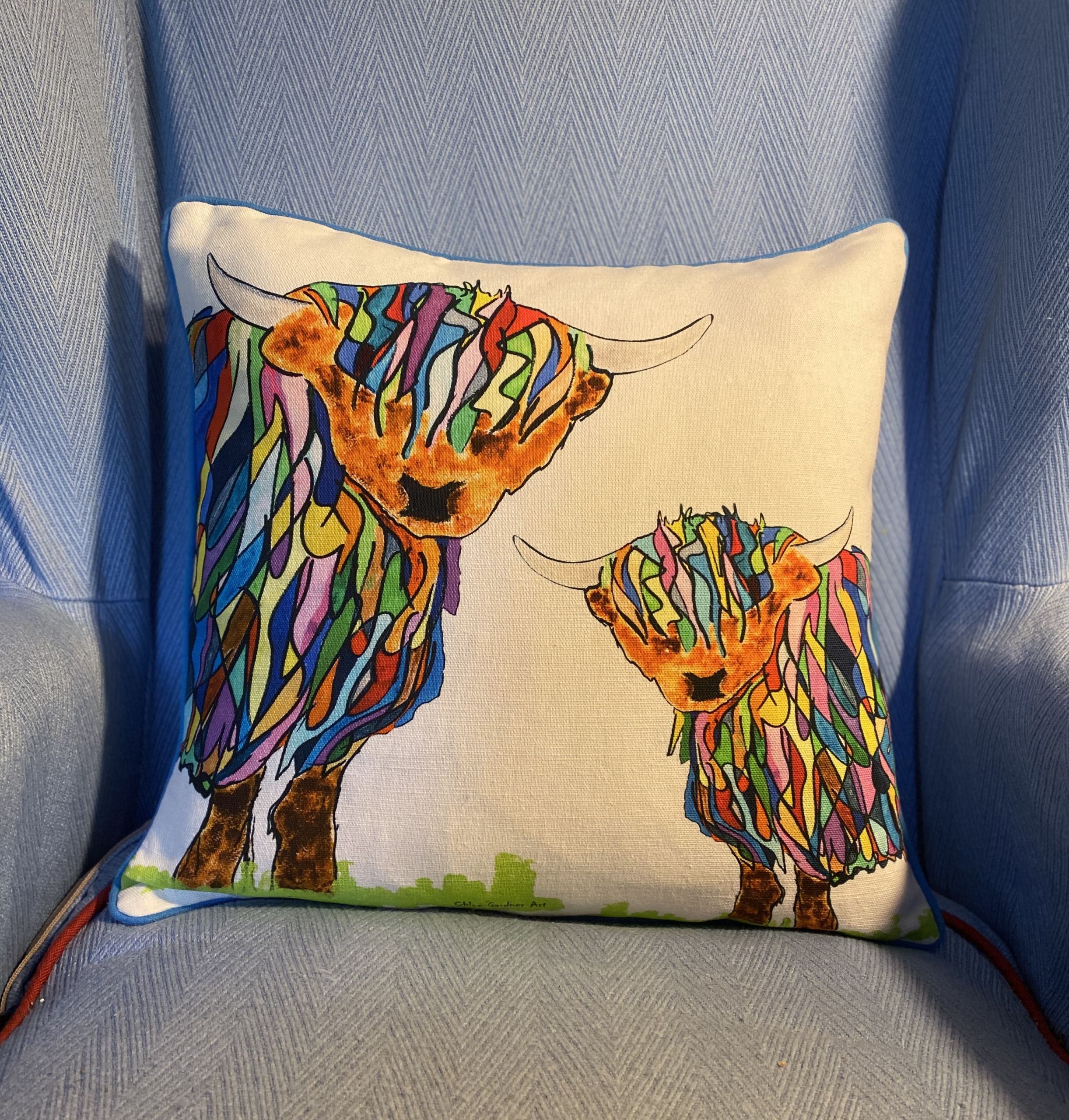 bright highland cow BHC and baby cushion on blue chair