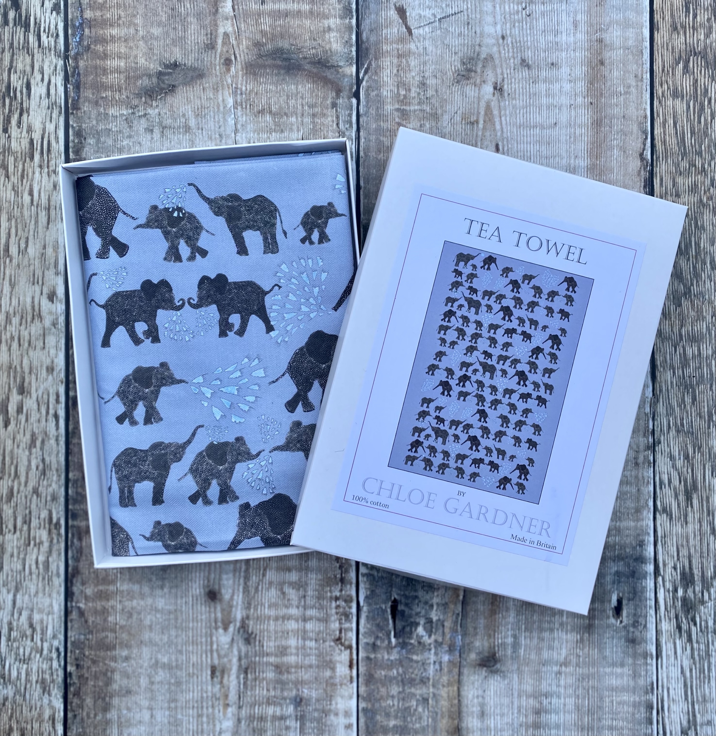 A GIFT BOXED TEA TOWEL - LOTS OF ELEPHANTS ON GREY
