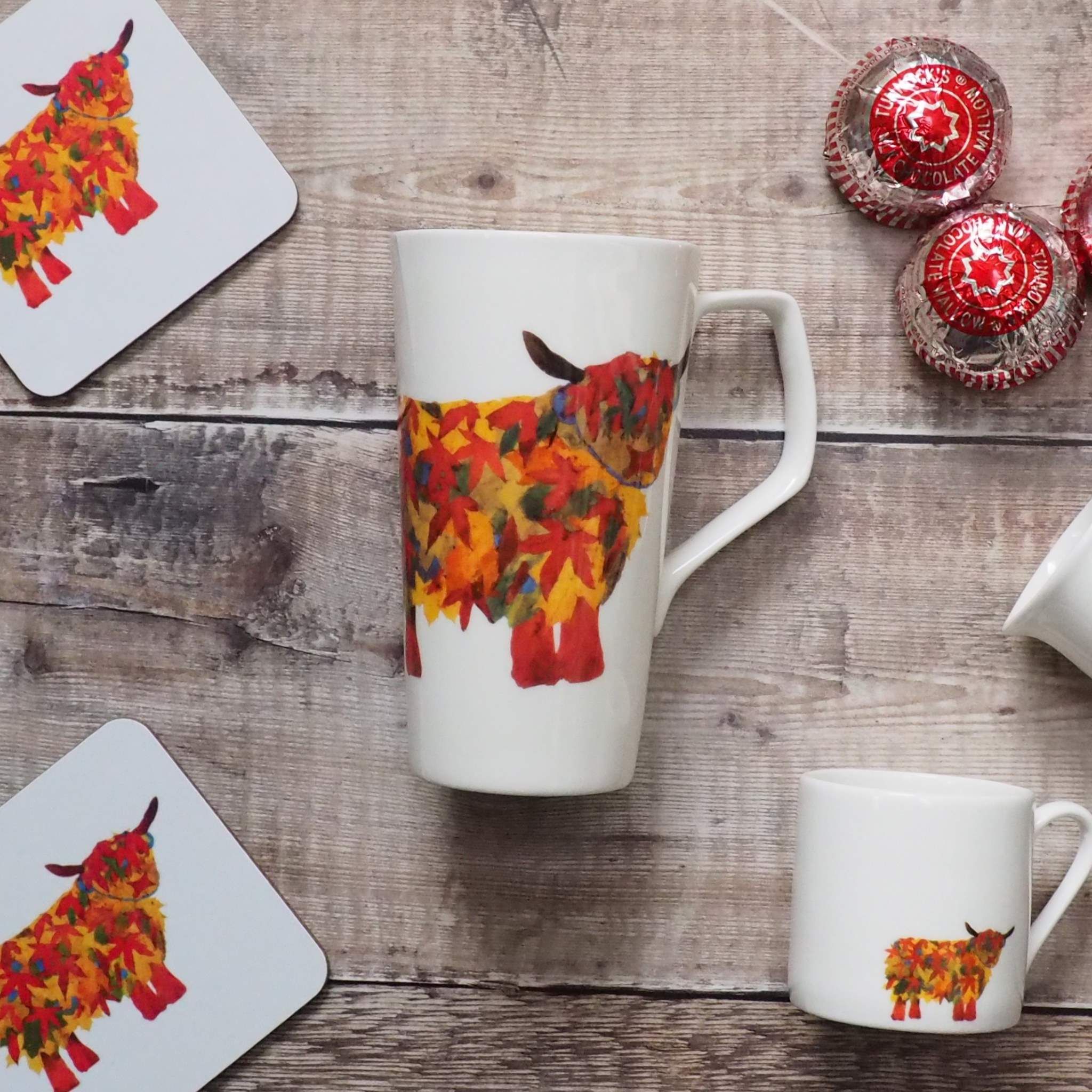Leaf Highland Cow Latte Mug surounded with leaf Cow Coaster and Leaf COw Espresso mug with teacakes on the side